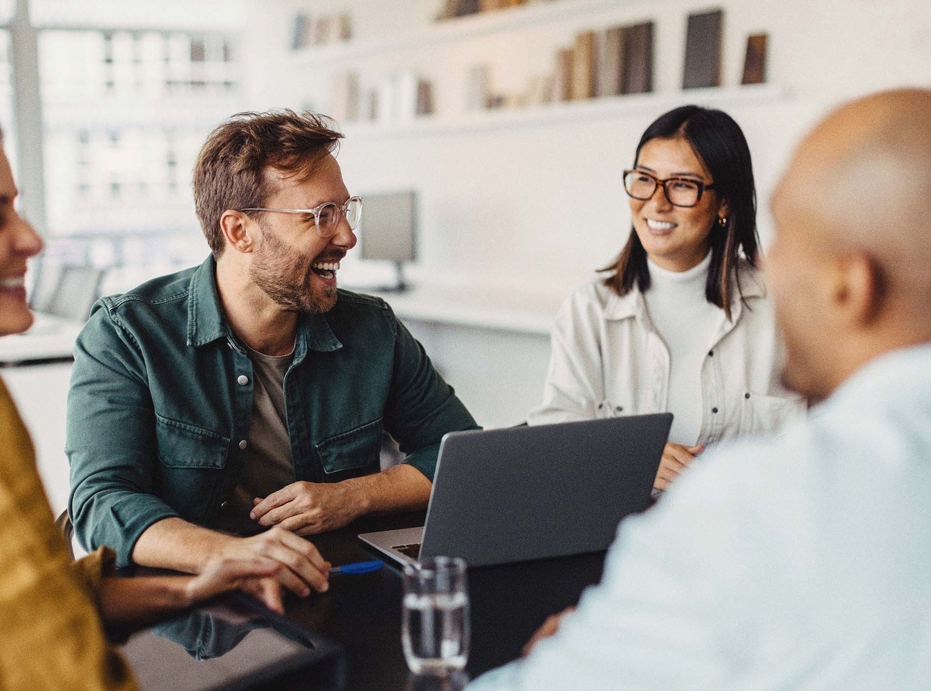 People smiling during a conversation around a laptop