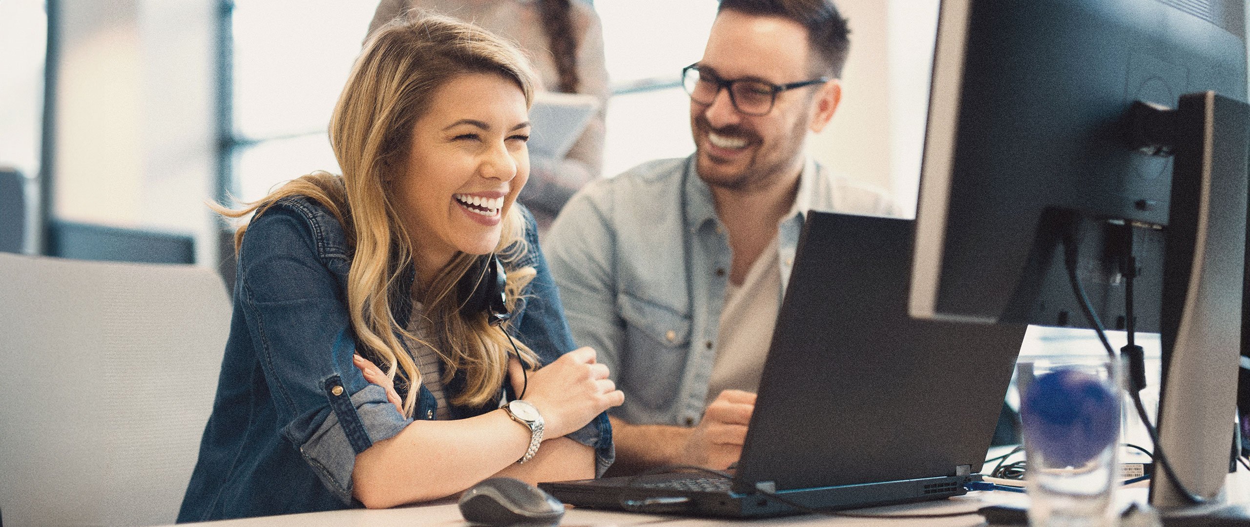 Two people sharing a moment of ease while working at a computer