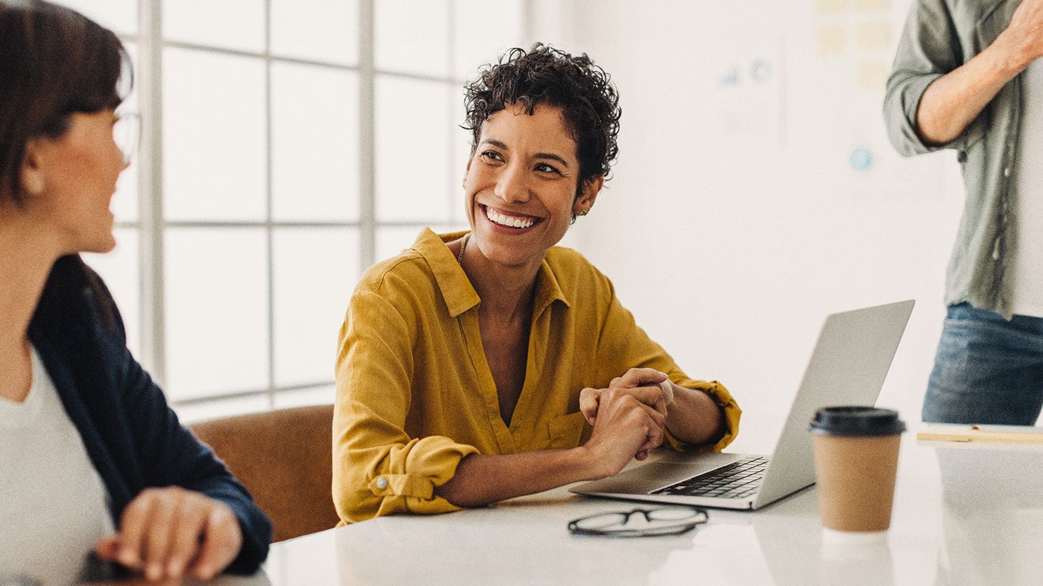 People sharing a relaxed conversation around a laptop