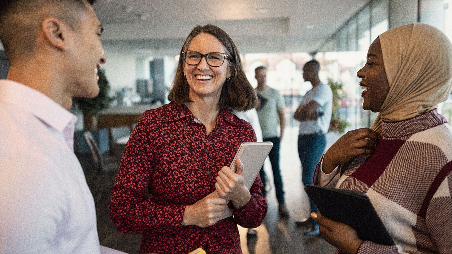 A person with glasses smiling during a conversation with colleagues